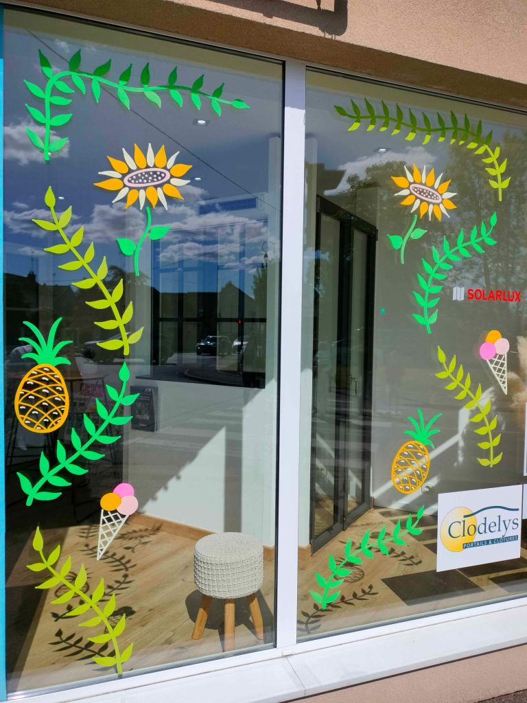 Peinture sur vitrine représentant des feuillages et des tournesols pour l'été pour le magasin Abbatienne de Menuiserie au Perray-en-Yvelines