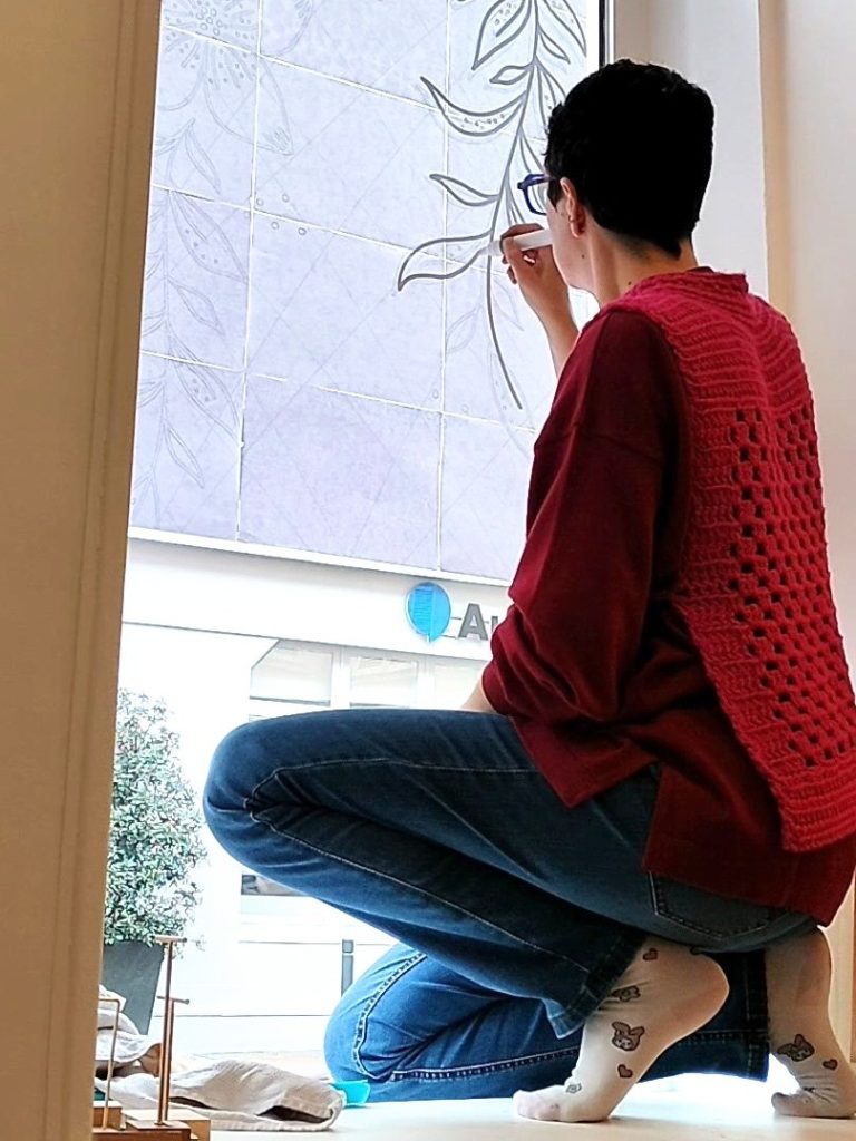 Camille Fauquet peignant un décor de feuillage sur une vitrine à Saint-Germain-en-Laye dans la boutique éphémère la Maison des Créateurs de l'association Créateurs Yvelines