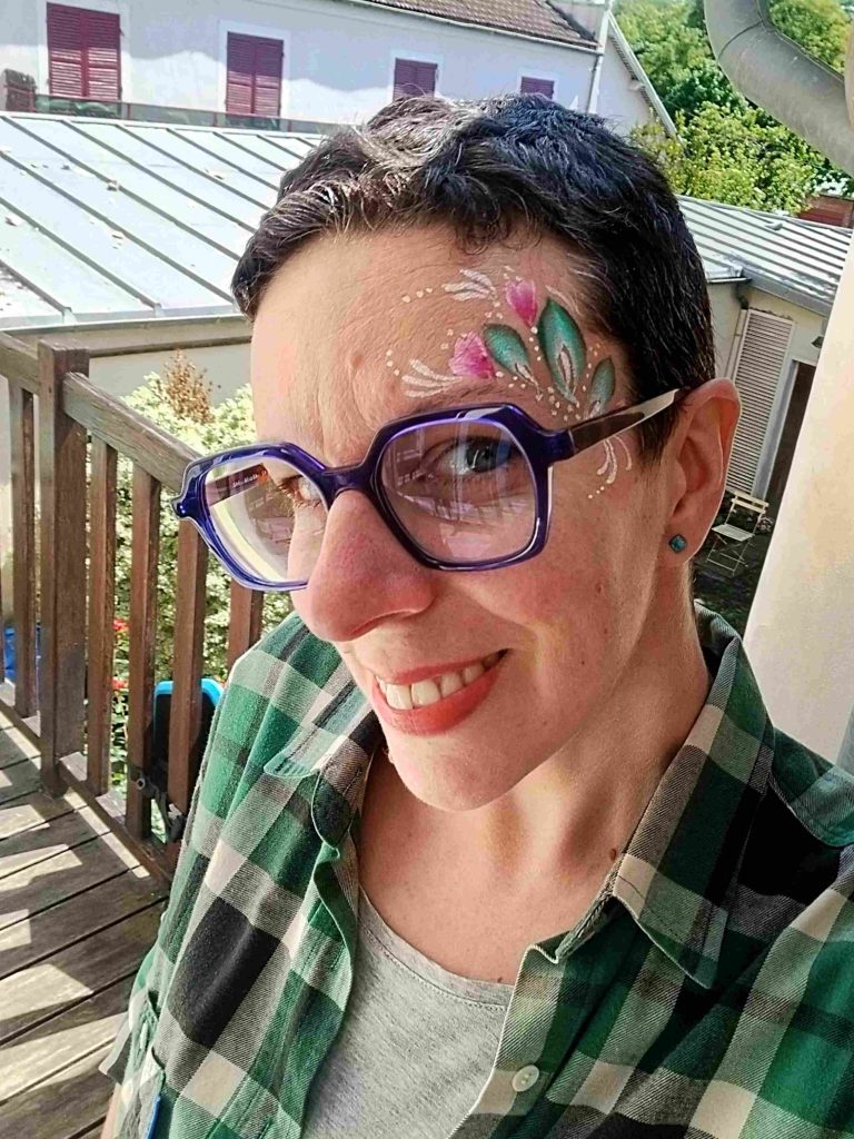 Selfie de Camille Fauquet avec un face-painting rose et vert végétal assorti à sa tenue