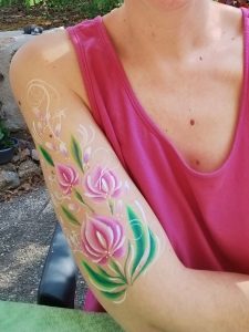 Fleurs roses peintes sur le bras avec la technique du body-painting, par Camille F créations