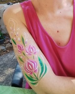 Fleurs roses peintes sur le bras avec la technique du body-painting, par Camille F créations