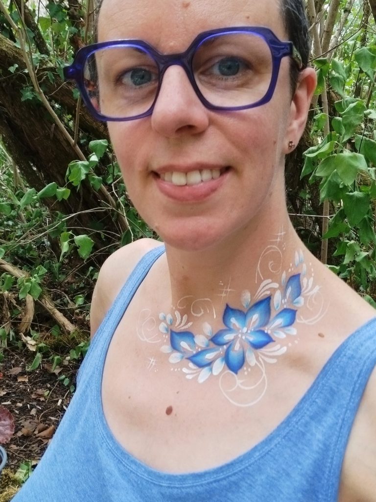 Fleurs bleues peintes sur le décolleté avec la technique du body-painting, par Camille F créations