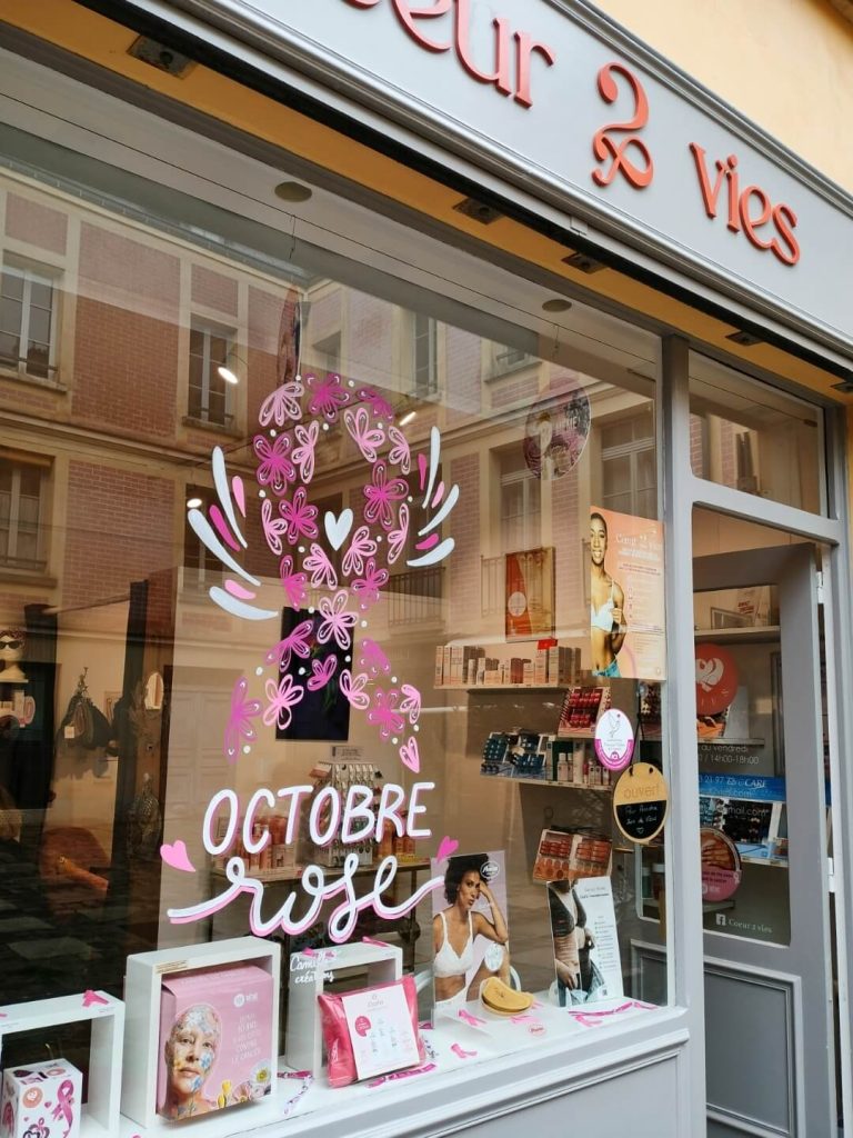 Peinture sur vitrine pour Octobre rose représentant le ruban fleur, chez Cœur 2 vies à Versailles, par Camille F créations